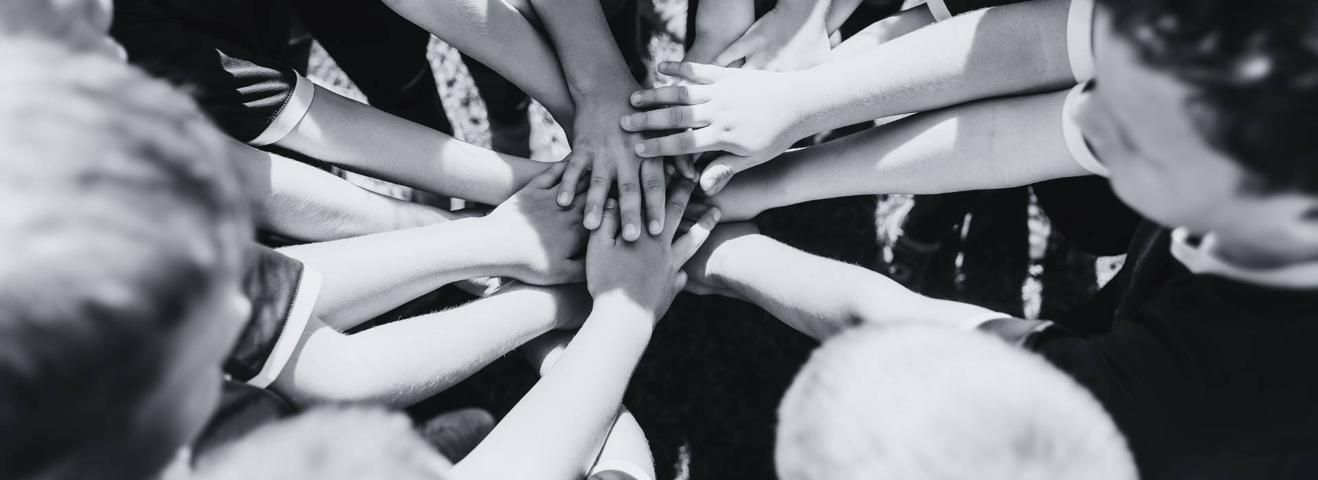 childrens sport team joining hands in the centre of a circle