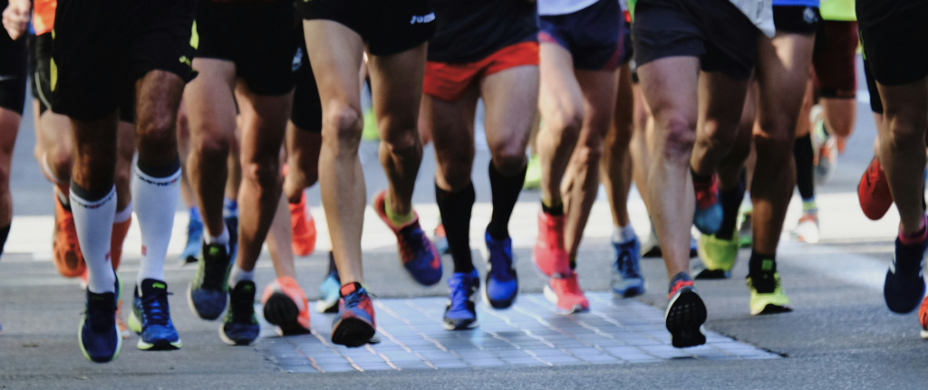 A group of road runners mid-stride shown from the waist down